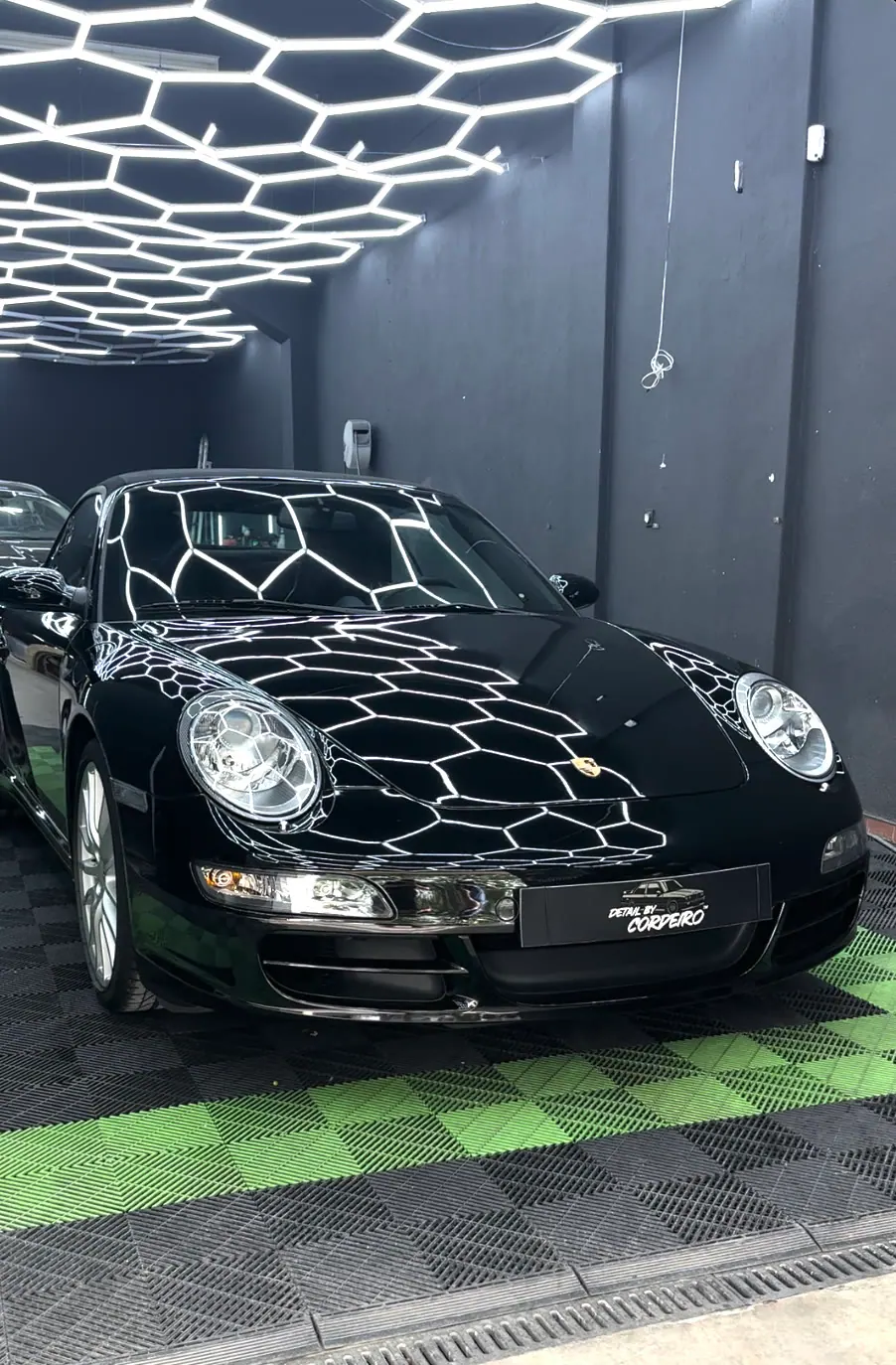 Porsche 911 preto a brilhar debaixo das luzes hexagonais do estúdio